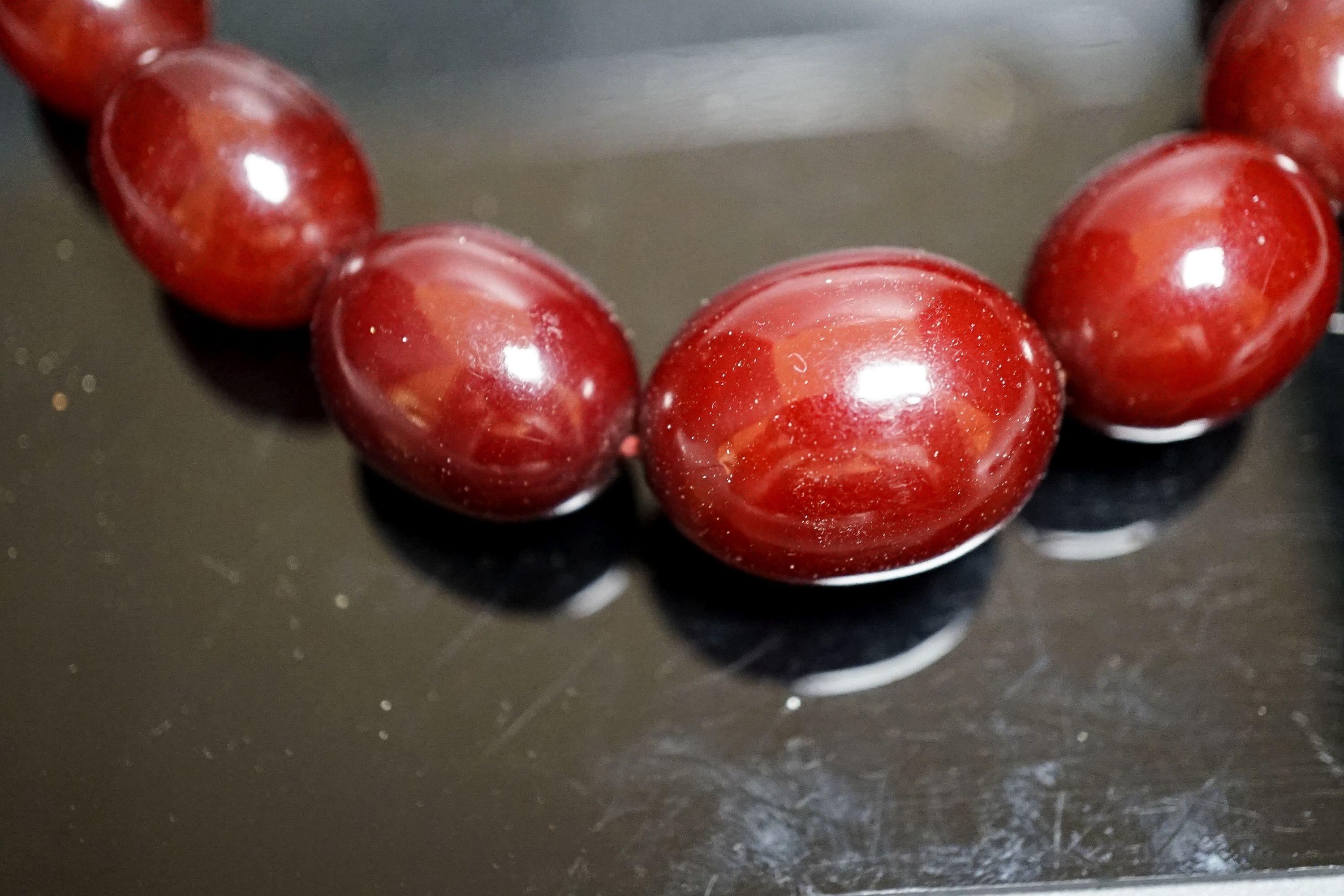 A single strand graduated simulated cherry amber oval bead necklace, 44cm, gross weight 78 grams.